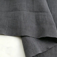 Two pieces of Longan Craft’s “Pure Color 100 Linen Fabric By The Yard,” crafted from 100% natural linen, overlap on a light surface, highlighting their soft texture and subtle weave pattern.