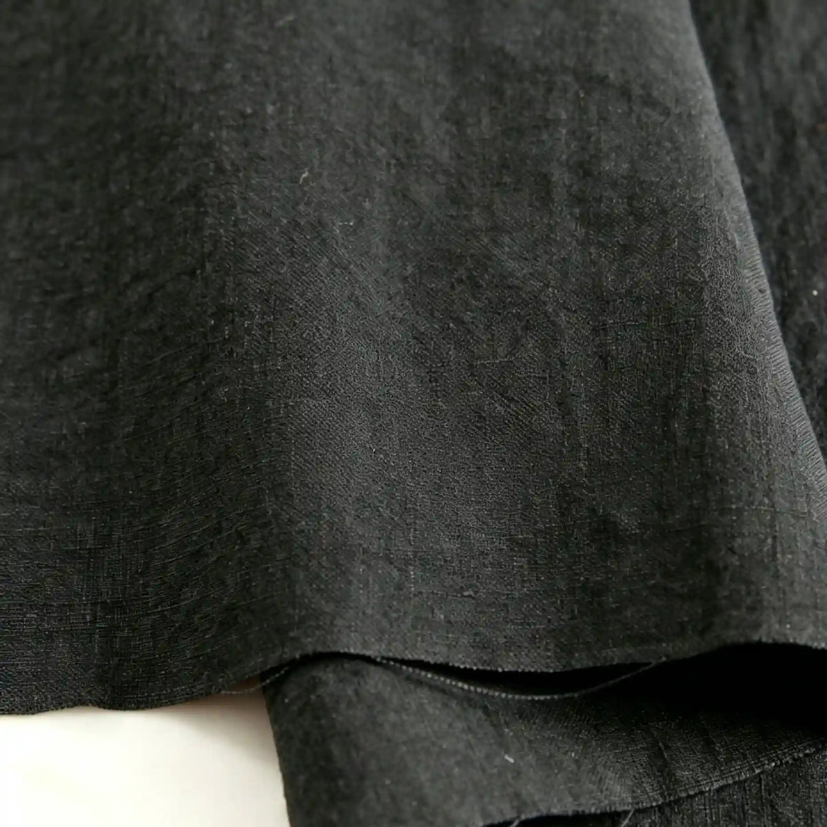 Close-up of Longan Craft’s Pure Color 100 Linen Fabric by the yard, showcasing its textured black medium-weight linen with soft folds, clearly visible weave patterns, and a slightly rough surface—ideal for comfy casual wear.