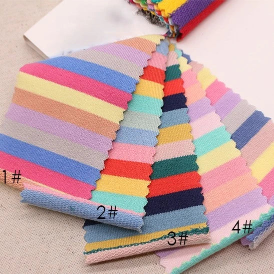 Four Rainbow Striped Stretch French Terry fabric swatches from Longan Craft, labeled 1#–4#, are neatly fanned out on a light surface. This soft cotton spandex knit is ideal for DIY sportswear sets and features pastel and bright horizontal stripes.