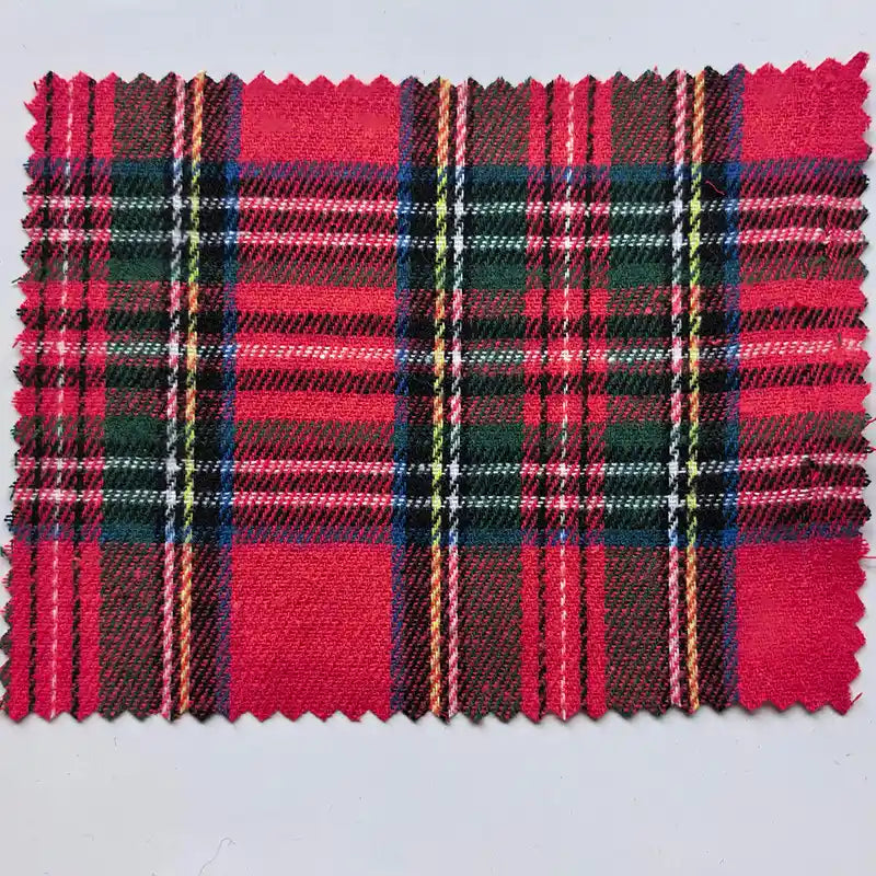 A rectangular piece of Longan Craft Red Checked Cotton Flannel Fabric By The Yard, featuring classic Scottish style with black, green, white, and yellow crisscrossed stripes and zigzag-cut edges, is displayed on a light background.