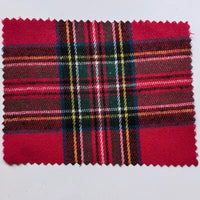 A rectangular sample of Longan Craft’s “Red Checked Cotton Flannel Fabric By The Yard” is shown here, featuring a Scottish-style vintage plaid pattern in red, green, yellow, black, and white. The single-sided brushed flannel material has zigzag pinked edges, displayed against a plain light gray background.
