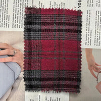 A piece of Longan Craft Red Checked Cotton Flannel Fabric By The Yard, featuring a vintage Scottish style with single sided brushed flannel material, rests atop a newspaper page, partially concealing images of hands holding bags.