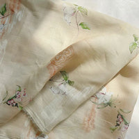 Retro Botanical Printed Ramie Fabric by Longan Craft is a light beige, lightweight ramie material featuring delicate pastel chinoiserie floral prints and green leaves with a subtle sheen, artfully draped in natural sunlight—perfect for blouses and creative projects by the yard.