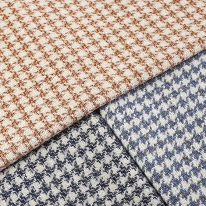 Three folded pieces of Longan Craft’s Retro Houndstooth Jacquard Tweed Fabric By The Yard—a wool polyester blend—are shown in light brown, blue, and black color combinations. These vintage-inspired tweed fabrics overlap neatly, emphasizing their classic houndstooth pattern and rich texture.