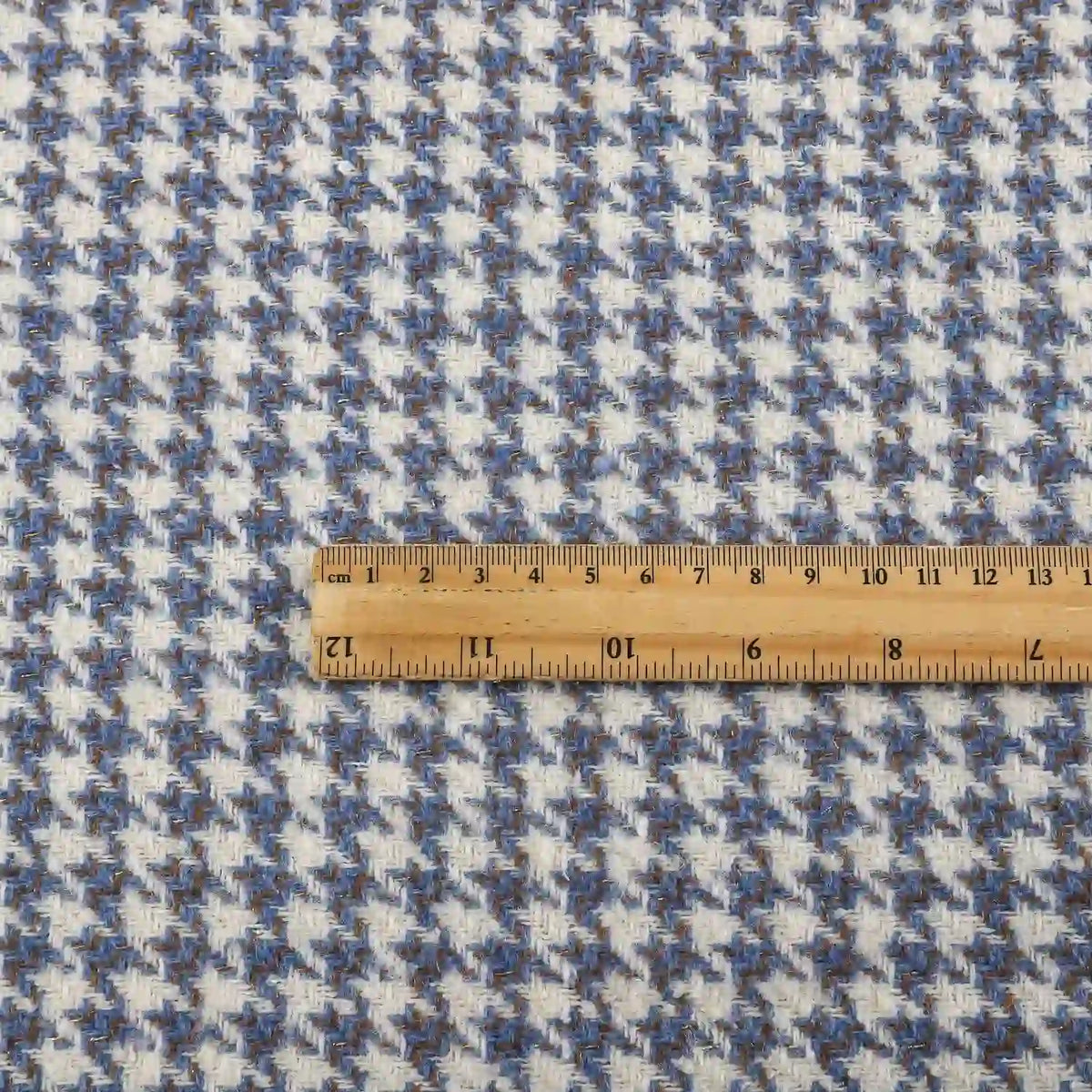A wooden ruler lies on Longan Craft’s Retro Houndstooth Jacquard Tweed Fabric by the yard, a wool polyester blend tweed material for coats, showcasing the scale of the vintage-inspired blue and white pattern.
