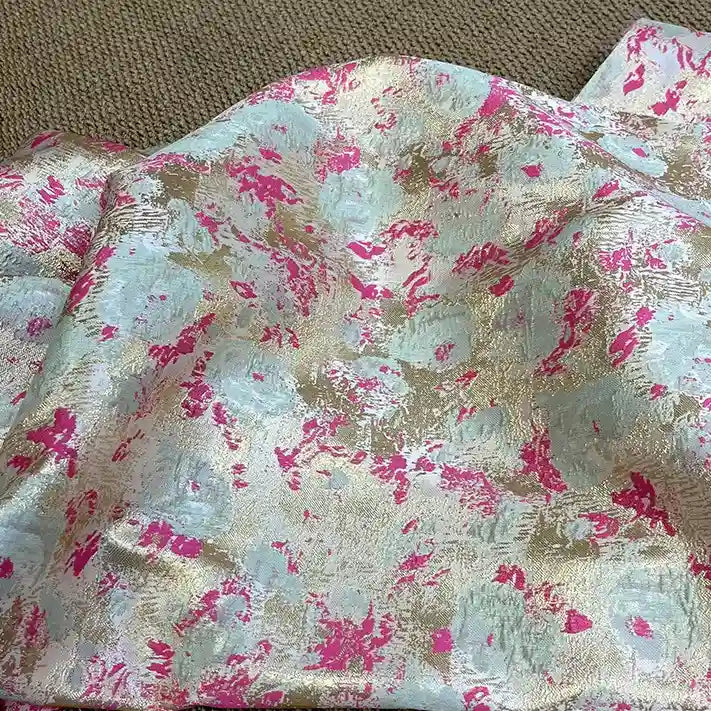 Rose Jacquard Brocade Fabric by Longan Craft, featuring golden metallic floral patterns with pastel blue and pink accents, shown draped over a beige carpet. Ideal retro brocade material for formal dresses, sold by the yard.