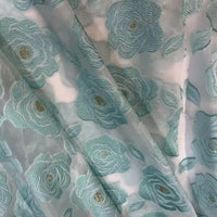 Rose Jacquard Organza Fabric by Longan Craft features a sheer, slightly transparent vintage material with embroidered blue-green and gold floral designs, highlighting its delicate jacquard weave—ideal for skirts and creative projects.