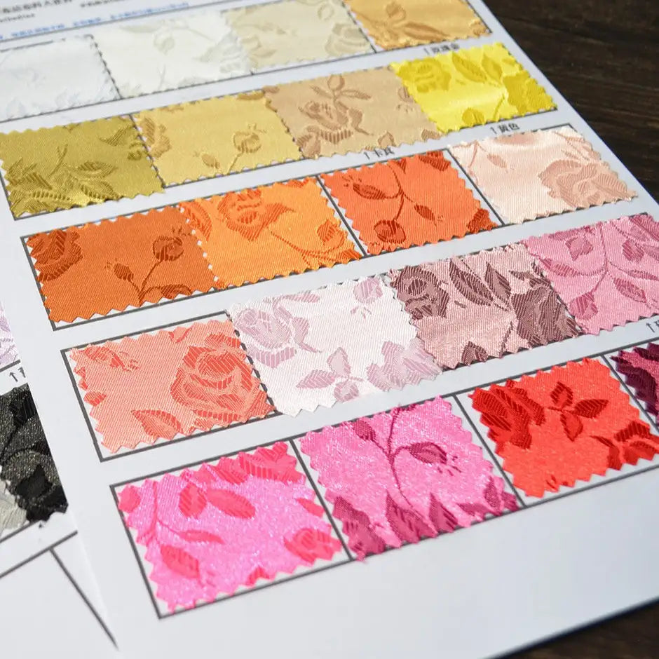 A sample sheet shows Rose Jacquard Satin Fabric By The Yard from Longan Craft, featuring rectangular swatches in yellow, orange, pink, white, and purple. Each displays intricate floral jacquard patterns in colorful polyester satin—perfect for costumes.