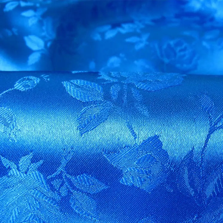 Close-up of colorful Rose Jacquard Satin Fabric by Longan Craft, featuring an intricate woven floral and leaf pattern. This smooth polyester satin is perfect for costumes, with its elegant shine reflecting off the detailed jacquard design.