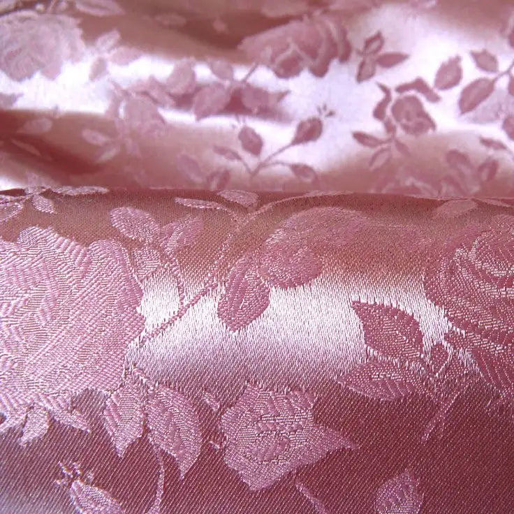 Close-up of Longan Craft's Rose Jacquard Satin Fabric by the yard, a colorful polyester textile with an elegant woven rose and leaf pattern—ideal for costumes and featuring a textured, shiny floral design.