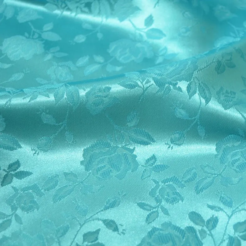Close-up of Longan Craft's Rose Jacquard Satin Fabric By The Yard, a colorful polyester satin with woven roses and leaves, showing embossed floral design, soft folds, and a silky reflective surface—ideal for costumes.