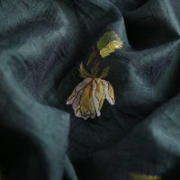 Longan Craft's Rose Printed Lyocell Fabric by the yard features botanical embroidery with yellow and white petals and green leaves. This breathable fabric for dressmaking showcases detailed texture and soft folds in natural lighting.