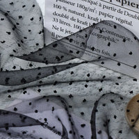 Sheer Swiss Dot Organza Fabric By The Yard draped over a paper bag with French text.