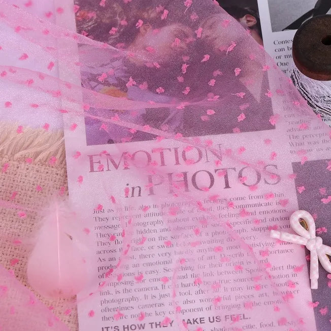 Sheer Swiss Dot Organza Fabric By The Yard draped over a page from a book titled Emotion in Photos.