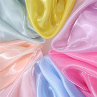 Close-up of Longan Craft’s Shiny Liquid Organza Fabric By The Yard, featuring pastel yellow, pink, blue, peach, and mint with a glossy finish arranged in folds—ideal for luxury evening wear or bridal gowns.