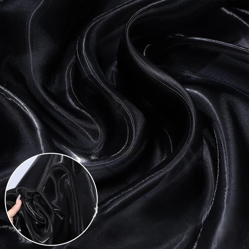 Close-up of Shiny Liquid Organza Fabric By The Yard from Longan Craft, featuring a colorful glossy finish with smooth folds—perfect for luxury gowns. Inset shows the semi-transparent textile being held and gently crumpled by hand.
