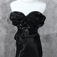 A mannequin displays a strapless evening dress made from Longan Craft's Shiny Liquid Organza Fabric By The Yard, featuring a colorful glossy finish and ruched details that enhance its fitted silhouette against a gray textured background.