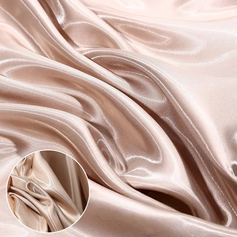 Close-up of Shiny Liquid Satin Fabric By The Yard from Longan Craft in light beige, showing its smooth, flowing folds and lustrous sheen—perfect for bridesmaid dresses and formalwear. A circular inset highlights its detailed texture.