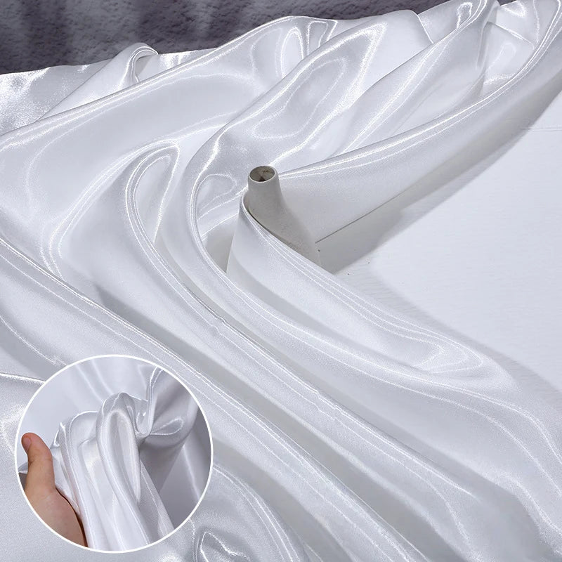 A close-up of Shiny Liquid Satin Fabric By The Yard from Longan Craft, draped smoothly, with an inset showing a hand gently holding the same glossy polyester satin—ideal for solid color bridesmaid dresses and formalwear textiles.