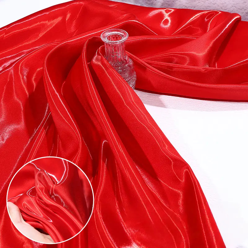 Shiny Liquid Satin Fabric by the Yard from Longan Craft, shown in red, draped over a clear glass vase with a close-up inset highlighting its smooth, reflective texture—ideal for solid color bridesmaid dresses and formalwear.