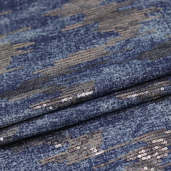 A close-up of Longan Craft's Shiny Sequin Embroidered Denim Fabric by the yard shows mottled, washed denim with sparkling silver sequins and cotton embroidery—ideal for dresses, skirts, and coats.