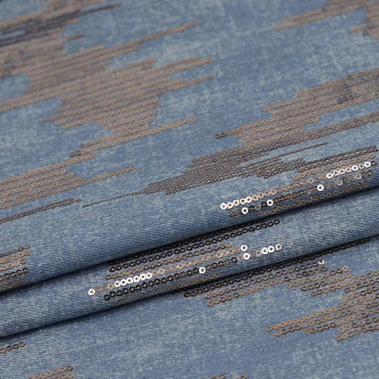 Shiny Sequin Embroidered Denim Fabric by Longan Craft features washed denim with cotton embroidery and shimmering silver sequin patterns, perfect for dresses, skirts, or coats. Available by the yard. Texture is smooth with a subtle gloss.
