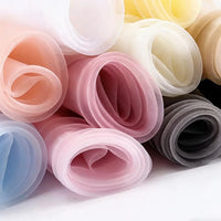 Close-up of Longan Craft Silky Polyester Organza Fabric by the yard—premium, soft, sheer solid color material—arranged in pastel rolls on a white surface, ideal for evening dresses and bridal gowns.