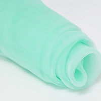 A close-up of Longan Craft’s Silky Polyester Organza Fabric by the Yard—premium, soft, and sheer bridal organza material in a solid light green color—rolled up on a white surface.