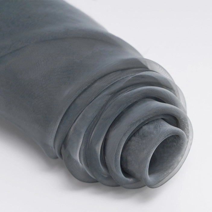 A close-up of Longan Craft's Silky Polyester Organza Fabric By The Yard showcases its soft, sheer, and lightweight premium material in gray—perfect for elegant evening dresses or bridal gowns. Displayed rolled on a white background.