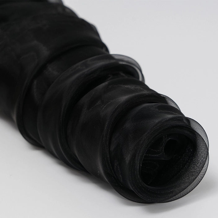 A close-up of Longan Craft Silky Polyester Organza Fabric by the Yard in solid black on a light gray background, showcasing its soft, sheer texture—perfect for premium evening dresses and bridal gowns.