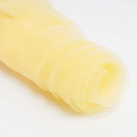 A close-up of Longan Craft's Silky Polyester Organza Fabric By The Yard in light yellow, partially unrolled on a white background. This premium, soft, sheer organza is ideal for bridal gowns and evening dresses.