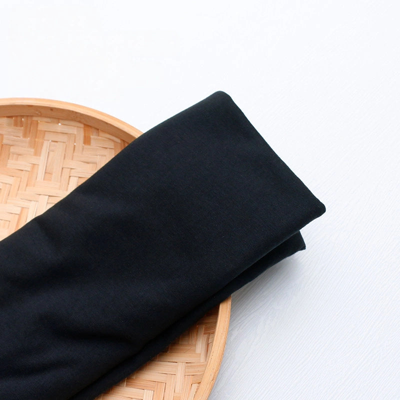 A vibrant polyester jersey fabric by the yard from Longan Craft, perfect for casual wear, is displayed on a round woven bamboo tray against a white background.