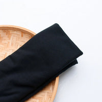 A vibrant polyester jersey fabric by the yard from Longan Craft, perfect for casual wear, is displayed on a round woven bamboo tray against a white background.