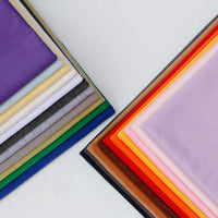 Longan Craft's Single Jersey Fabric By The Yard features colorful polyester jersey material—purple, yellow, green, gray, and more—neatly stacked on a white background, perfect for casual wear.