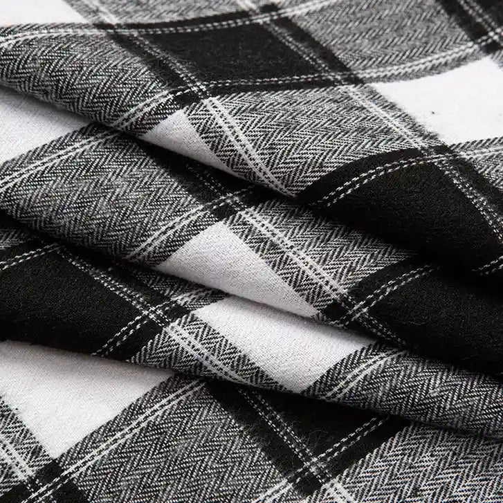 Close-up of folded Longan Craft Single Sided Sueded Plaid Flannel Fabric By The Yard, featuring a black, white, and gray plaid pattern. The medium weight polyester cotton flannel showcases premium soft texture with detailed woven intersecting lines and chevron-like designs within the darker stripes—ideal for clothing and craft projects.