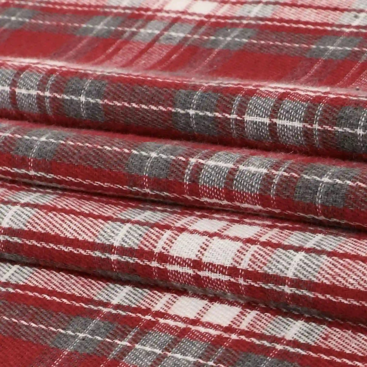 Close-up of folded Longan Craft Single Sided Sueded Plaid Flannel Fabric By The Yard, featuring a red, white, and gray plaid pattern. The medium weight polyester cotton blend and the sueded texture of this premium soft flannel clothing material are clearly visible.