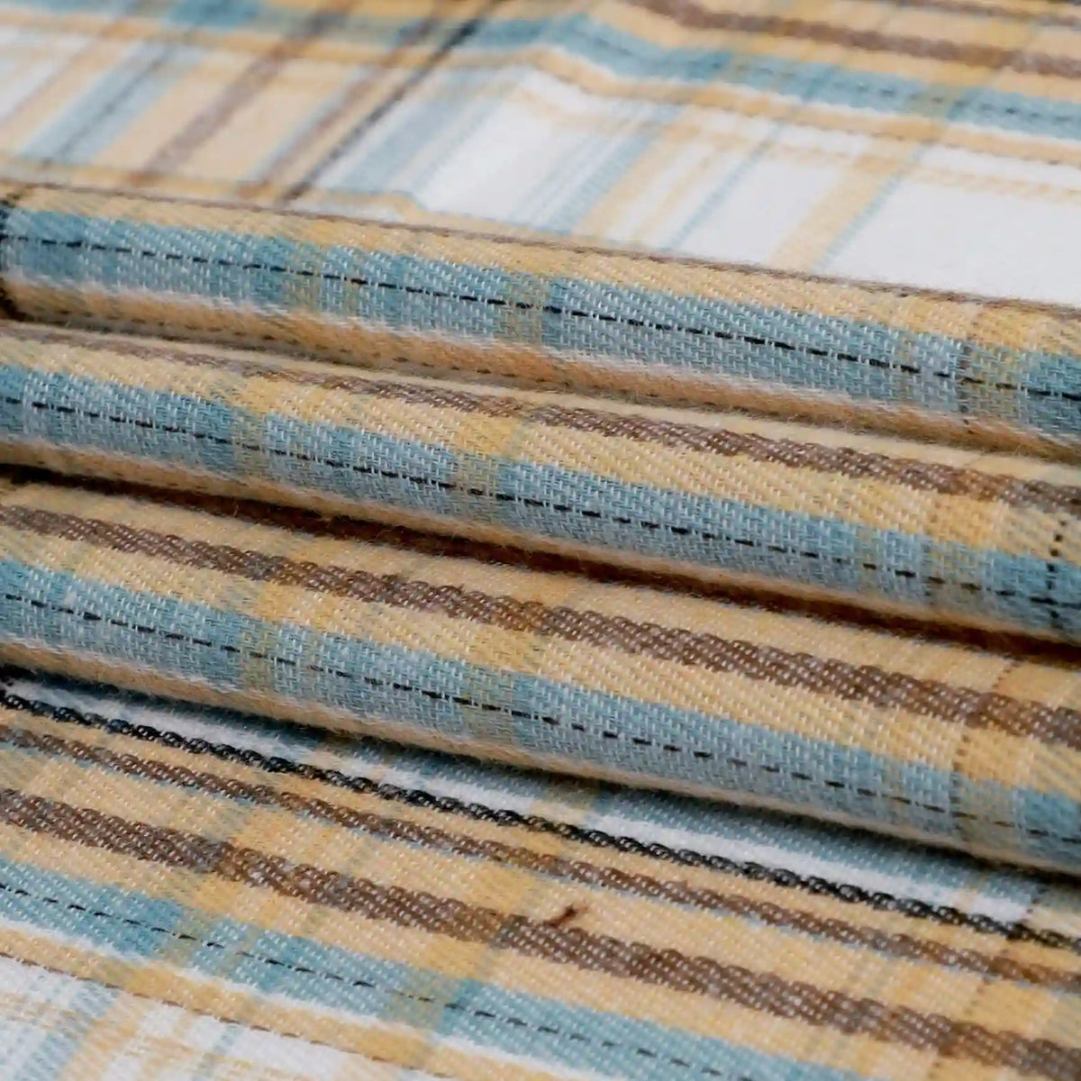 The Longan Craft Single Sided Sueded Plaid Flannel Fabric By The Yard features a classic plaid pattern in beige, blue, and brown tones with textured woven fibers and intersecting lines. This premium medium weight polyester cotton flannel textile offers a soft sueded finish, perfect for clothing projects.