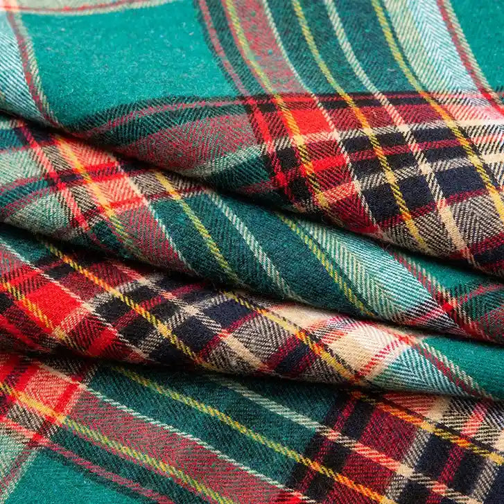 A close-up view of the Single Sided Sueded Plaid Flannel Fabric By The Yard from Longan Craft displays its red, green, yellow, blue, and white plaid design. The image highlights the brushed fibers and textured softness of this premium medium weight polyester cotton flannel textile, emphasizing its cozy warmth—perfect for any sewing or craft project.