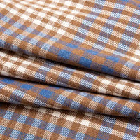 The Single Sided Sueded Plaid Flannel Fabric by the yard from Longan Craft features a premium soft, medium weight polyester cotton blend with a brown, blue, and white checkered pattern. The fabric is neatly folded in overlapping layers, showcasing its soft flannel texture—ideal for clothing and crafts.