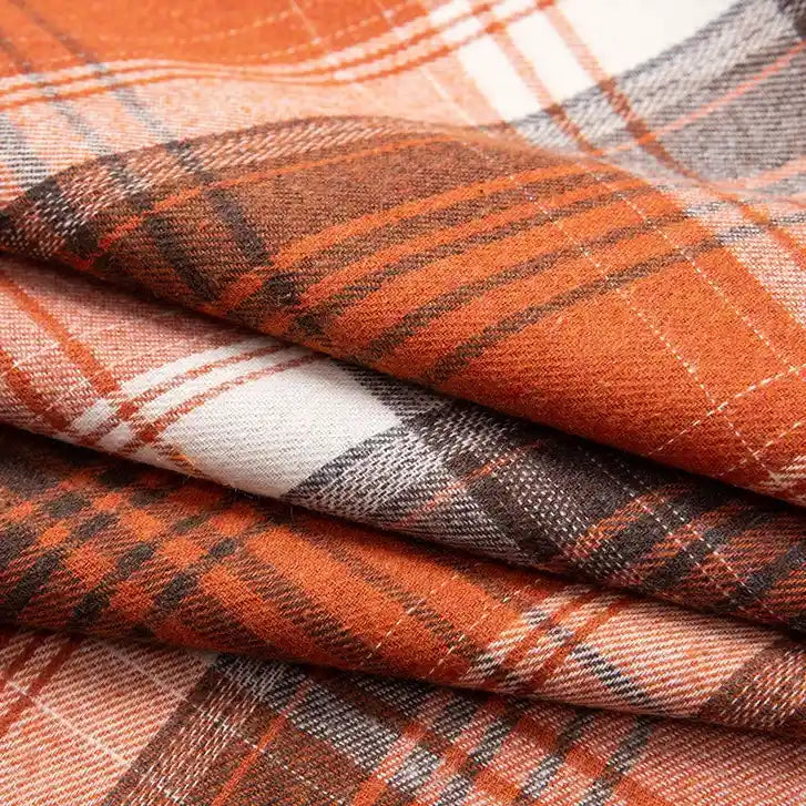 Close-up of folded Single Sided Sueded Plaid Flannel Fabric by the yard from Longan Craft, featuring medium weight polyester cotton with intersecting lines in orange, brown, and white and a premium soft brushed texture—ideal for cozy flannel clothing projects.