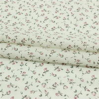 Longan Craft's Small Floral Printed Voile Fabric by the yard is 100% cotton with a botanical pattern of small pink roses and green leaves on a white background—perfect as a soft, lightweight material for summer clothing.