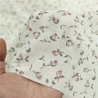 A hand holds Longan Craft's Small Floral Printed Voile Fabric—100% cotton voile by the yard, featuring a soft botanical pattern with pink roses and green leaves, perfect for summer clothing.