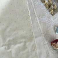 A close-up of Longan Craft’s Small Polka Dot Printed Lawn Fabric by the yard, a lightweight 100% cotton material, shown beside lace and dried roses with sliced lemons on a tray in the corner.