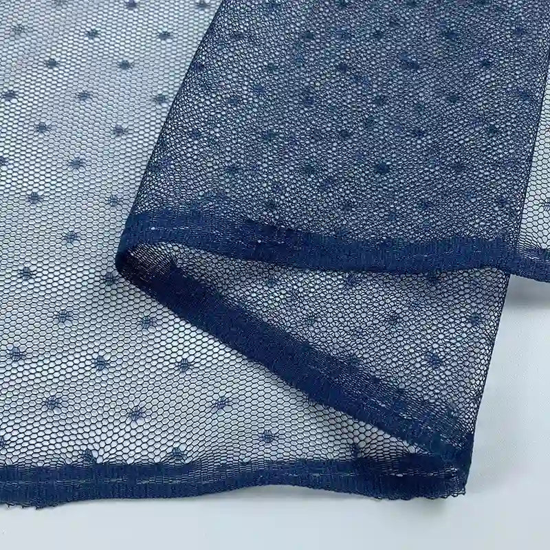 Close-up of Small Polka Dot Tulle Fabric By The Yard from Longan Craft—colorful polyester tulle with delicate embroidered dots, perfect for dresses or veils. Soft material shown in navy blue with folded edge.