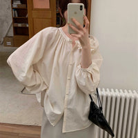 A person wearing the Longan Craft Smocked Crewneck Raglan Sleeve Blouse, made from the free PDF sewing pattern, holds a black bag and takes a mirror selfie indoors.