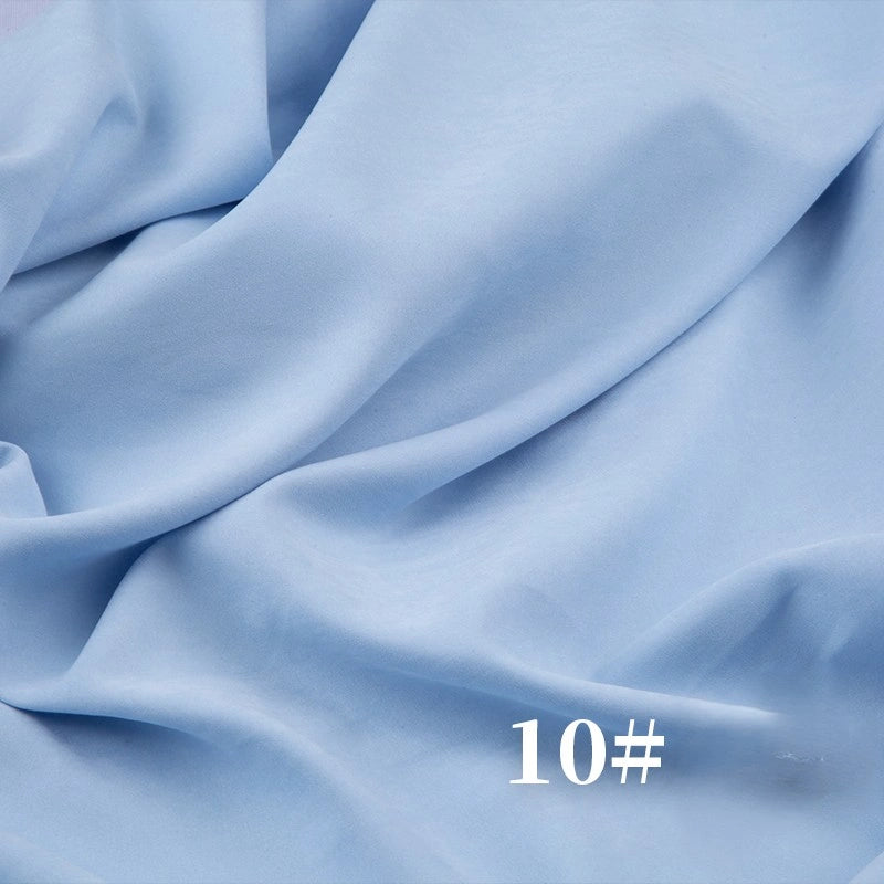 Longan Craft’s Solid Color Brushed Polyester Peachskin Fabric in light blue drapes softly with a flowing, velvety texture. White “10#” text appears in the lower right corner. Ideal for dressmaking and sold by the yard.