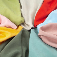 Longan Craft’s Solid Color Brushed Polyester Peachskin Fabric features midweight microsuede in green, yellow, pink, beige, red, blue, and peach—offering a soft, velvety texture ideal for vibrant dressmaking projects.