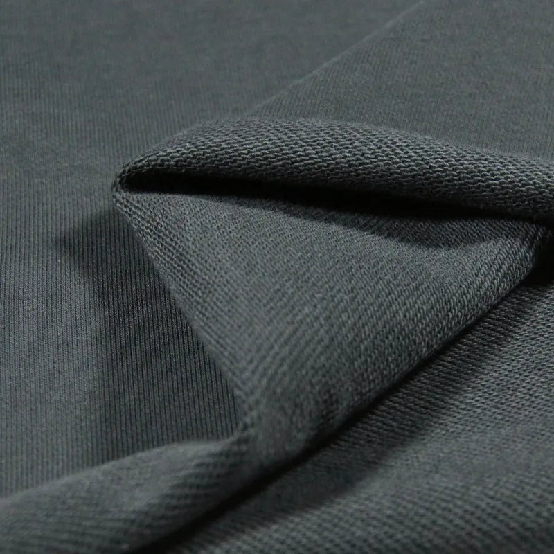 Close-up of Longan Craft Solid Color Cotton French Terry Fabric by the yard in dark gray, folded to show its smooth front and textured back—perfect thick material for hoodies and sweatshirts.