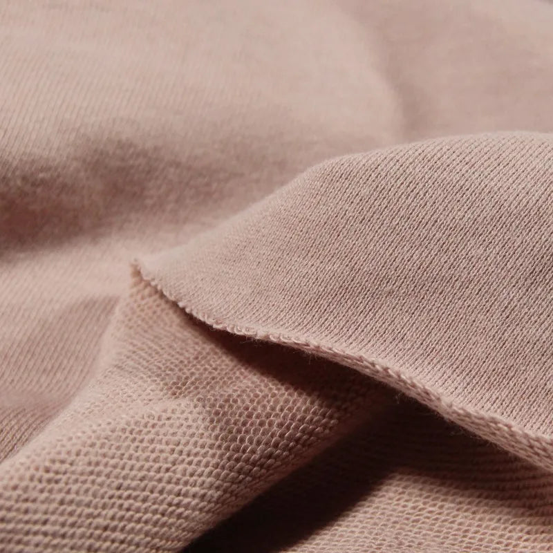A close-up of Longan Craft's Solid Color Cotton French Terry Fabric By The Yard highlights its soft, thick texture and weave, ideal for hoodies. Slight folds show the difference between the outer and inner surfaces.