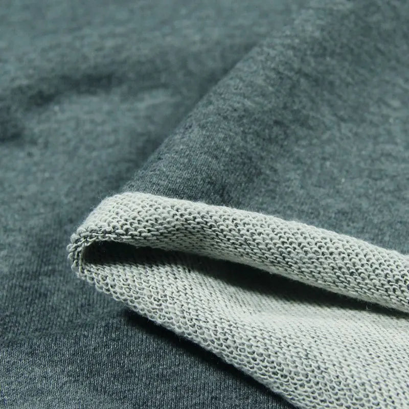 A close-up of Longan Craft’s Solid Color Cotton French Terry Fabric By The Yard, featuring a thick material with a smooth outer side and a textured, lighter inner side—ideal for hoodies and cozy apparel.